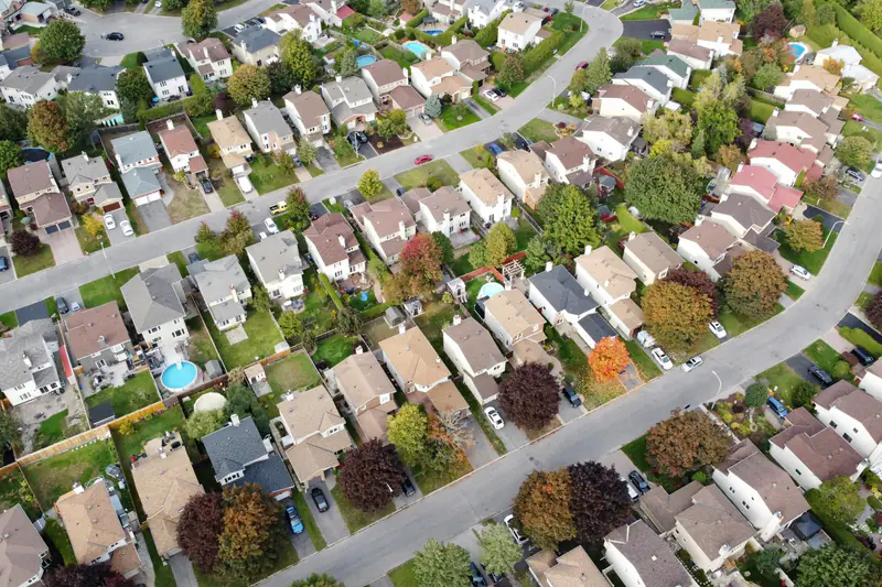 An aerial view of a suburban neighborhood with rows of houses, curving streets and trees